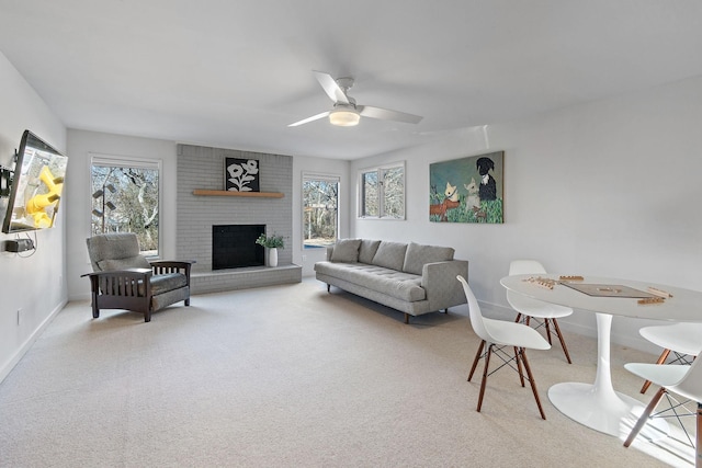 carpeted living room featuring baseboards, plenty of natural light, a ceiling fan, and a brick fireplace