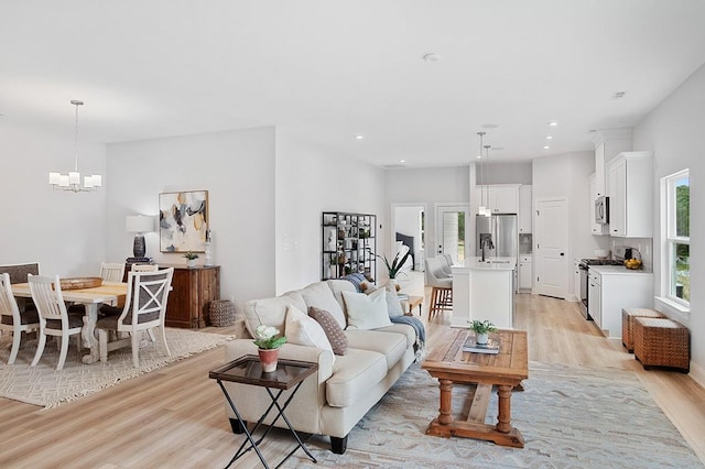 living room featuring recessed lighting, an inviting chandelier, and light wood-style flooring