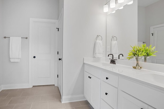 full bath featuring double vanity, tile patterned floors, baseboards, and a sink