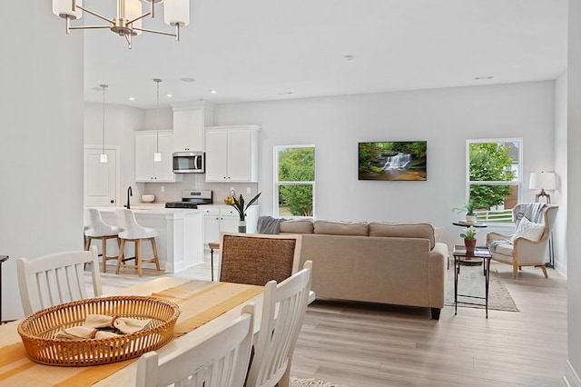 dining room featuring light wood-style flooring, a notable chandelier, and recessed lighting