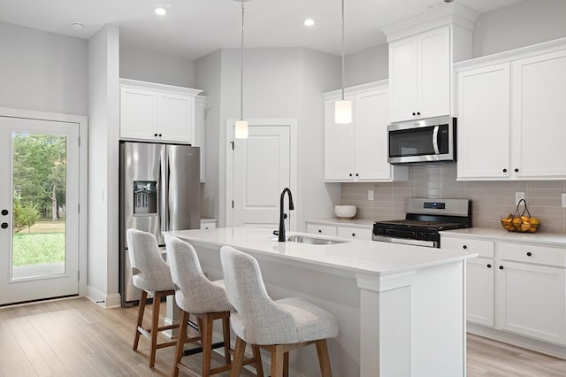 kitchen featuring a sink, a center island with sink, backsplash, and stainless steel appliances