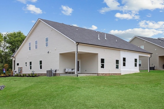 rear view of property featuring cooling unit, a shingled roof, and a yard