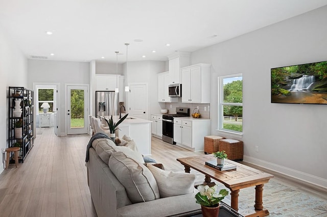 living room featuring recessed lighting, visible vents, baseboards, and light wood-style floors