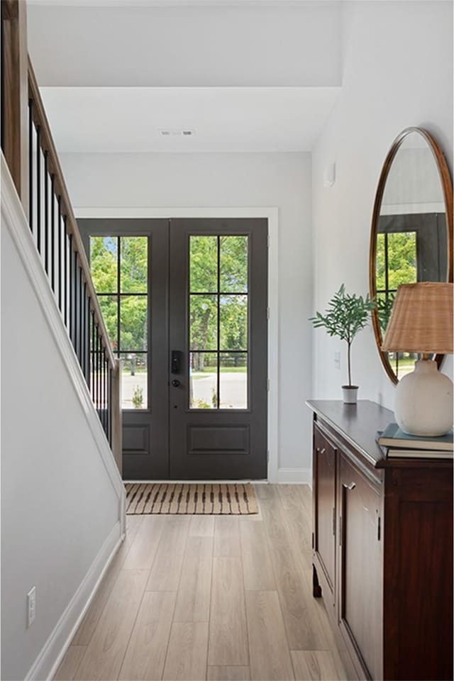 entrance foyer with light wood-style flooring, french doors, stairs, and baseboards