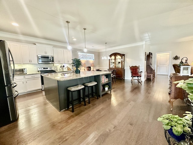 kitchen with tasteful backsplash, wood finished floors, stainless steel appliances, crown molding, and white cabinetry