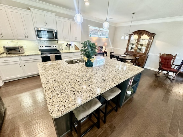 kitchen with dark wood-style floors, ornamental molding, a breakfast bar, stainless steel appliances, and white cabinetry