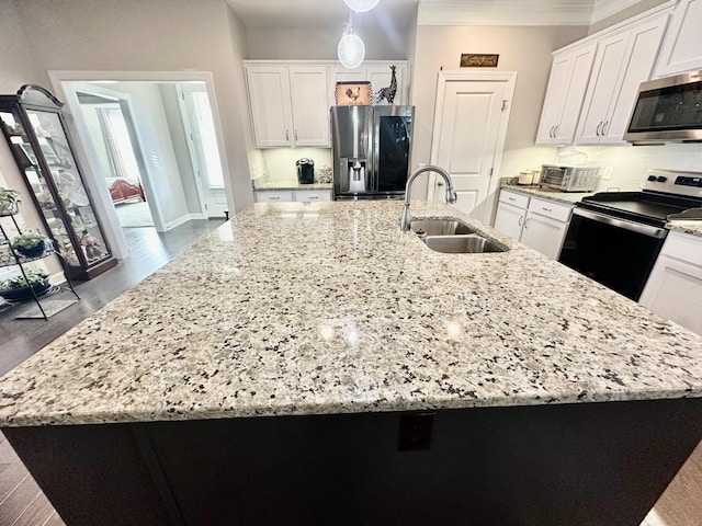 kitchen featuring white cabinets, ornamental molding, stainless steel appliances, a large island with sink, and a sink