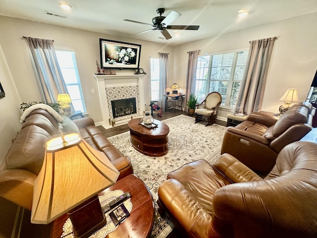 living room featuring a healthy amount of sunlight, visible vents, a tiled fireplace, and wood finished floors