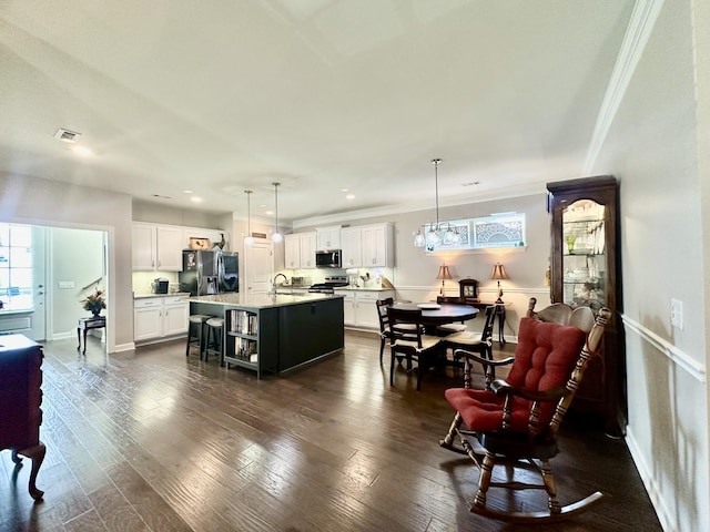 kitchen featuring a breakfast bar, visible vents, appliances with stainless steel finishes, and dark wood finished floors