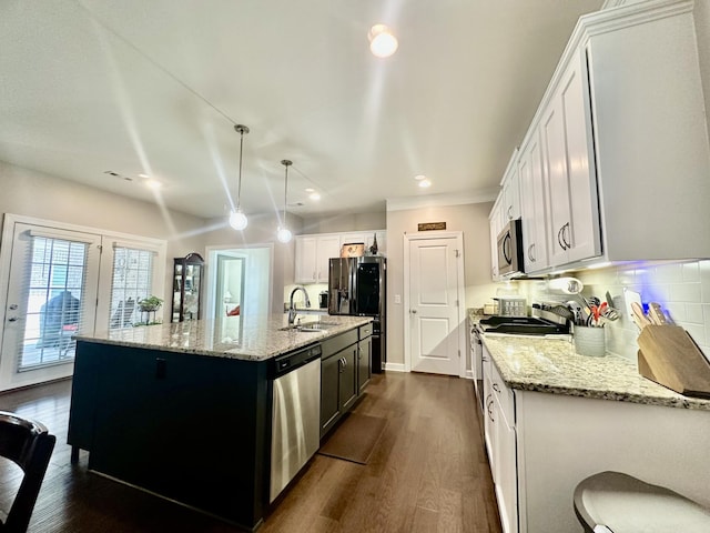 kitchen with light stone counters, decorative backsplash, appliances with stainless steel finishes, dark wood-type flooring, and a sink