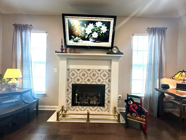 sitting room featuring baseboards, a tiled fireplace, and wood finished floors