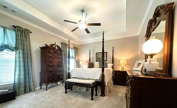 bedroom with a ceiling fan, a tray ceiling, visible vents, and light carpet