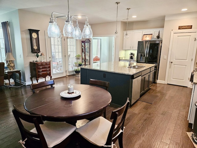 kitchen featuring a kitchen island with sink, a sink, refrigerator with ice dispenser, dishwasher, and dark wood finished floors