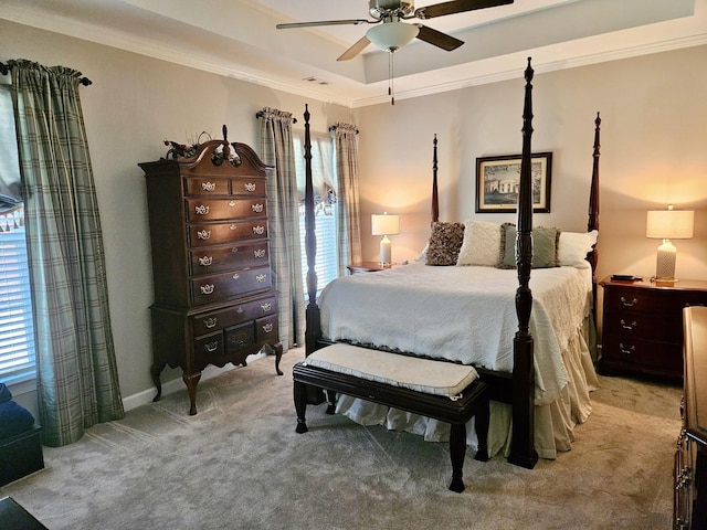 bedroom with carpet floors, ceiling fan, a tray ceiling, and ornamental molding