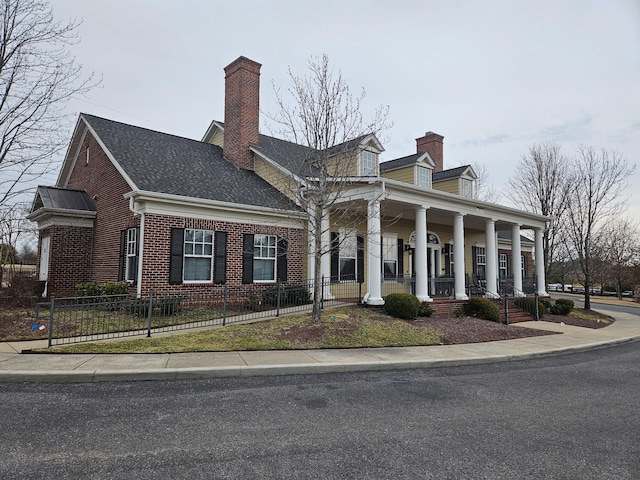 view of front of house featuring a fenced front yard, covered porch, brick siding, and a chimney