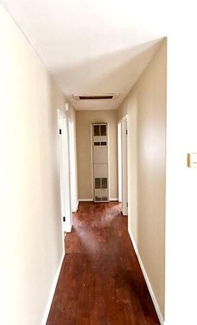 hall with dark wood-style floors, visible vents, and baseboards