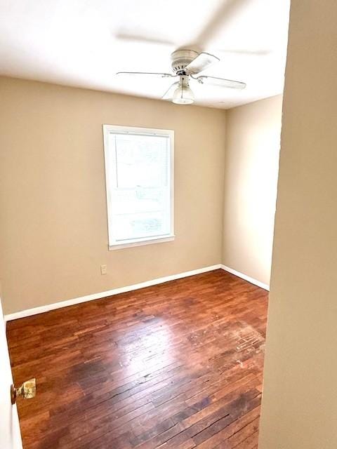 spare room with dark wood-style floors, ceiling fan, and baseboards