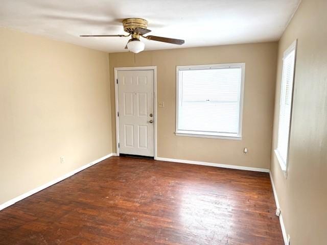 unfurnished room featuring baseboards, ceiling fan, dark wood-type flooring, and a healthy amount of sunlight