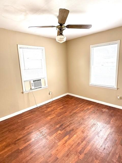 spare room with wood finished floors, cooling unit, a ceiling fan, and baseboards