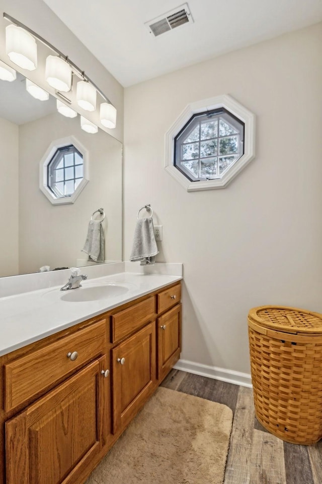 bathroom featuring visible vents, vanity, baseboards, and wood finished floors