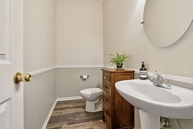 bathroom with wainscoting, a sink, toilet, and wood finished floors