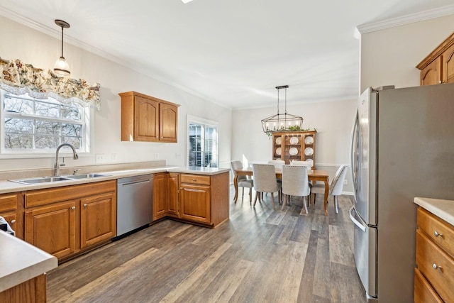 kitchen with appliances with stainless steel finishes, pendant lighting, light countertops, and a sink