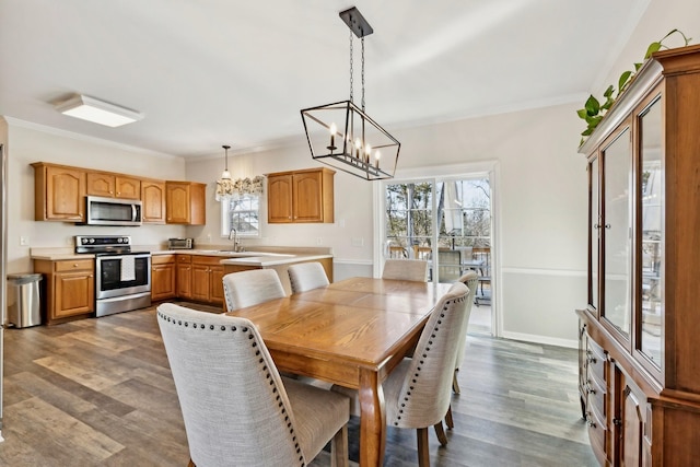 dining space featuring dark wood-type flooring, a chandelier, crown molding, and baseboards