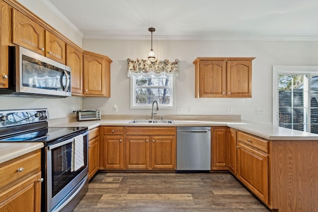 kitchen featuring pendant lighting, light countertops, appliances with stainless steel finishes, a sink, and a peninsula