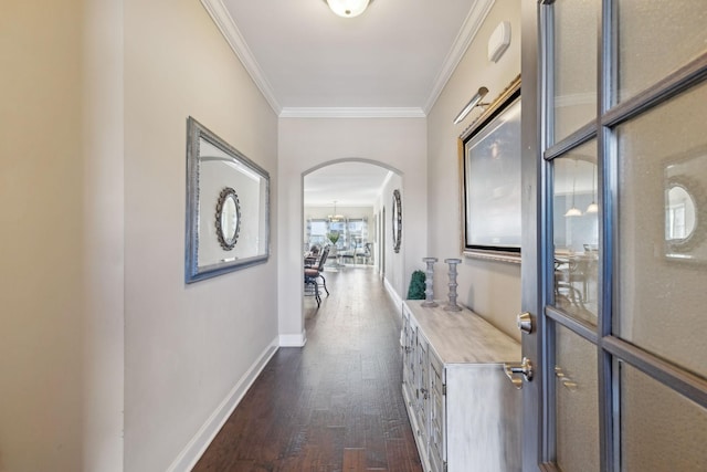 hall featuring baseboards, arched walkways, dark wood finished floors, and crown molding