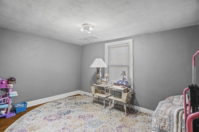 bedroom featuring dark wood-style floors, visible vents, a textured ceiling, and baseboards