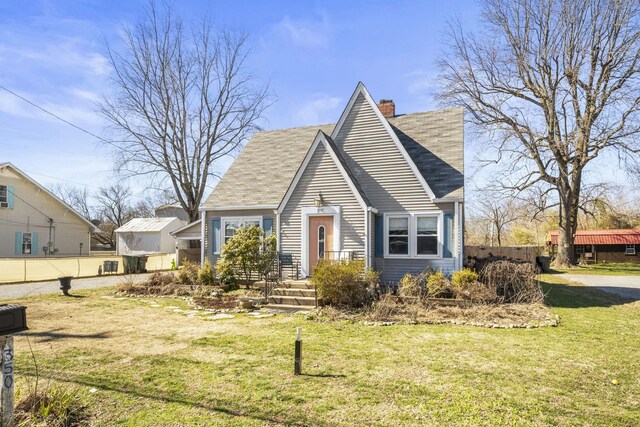 view of front of house with roof with shingles, fence, a chimney, and a front lawn