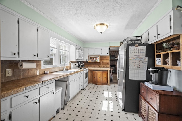 kitchen with white appliances, white cabinets, tile countertops, ornamental molding, and light floors