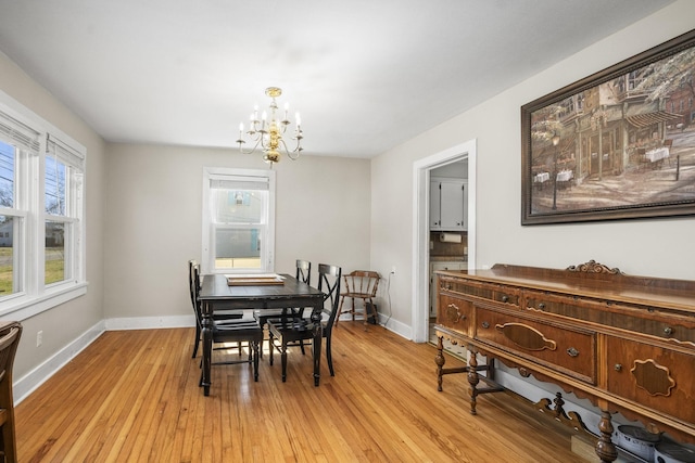 dining space featuring baseboards, light wood-style floors, plenty of natural light, and an inviting chandelier