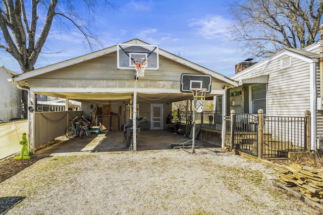 view of front of home with a carport, gravel driveway, and fence