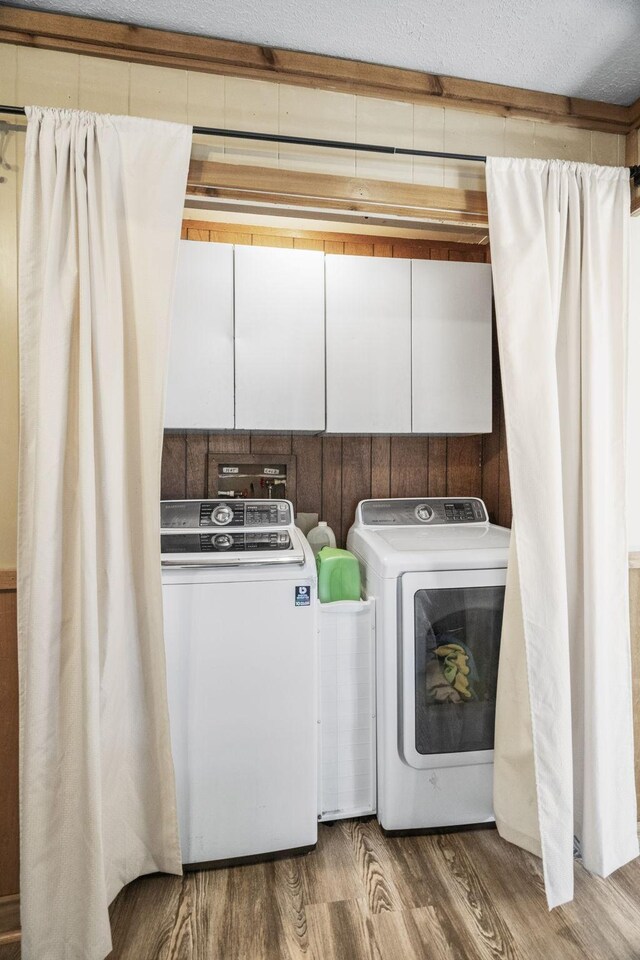 washroom with a textured ceiling, laundry area, wood finished floors, and washer and dryer