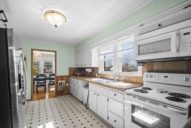 kitchen with tile countertops, light floors, white cabinets, a sink, and white appliances