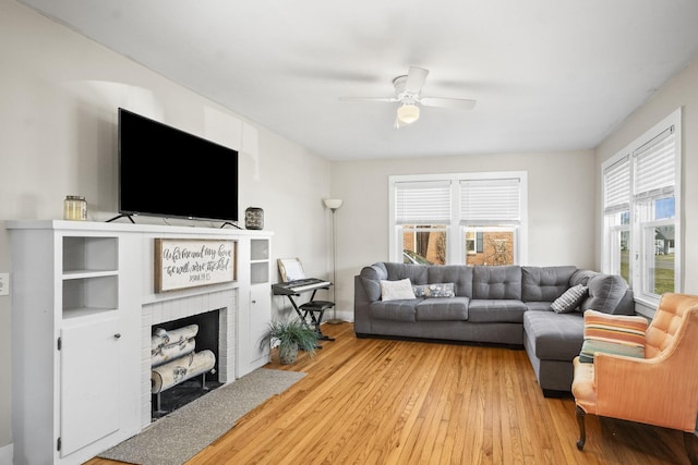living room with a brick fireplace, ceiling fan, and wood-type flooring