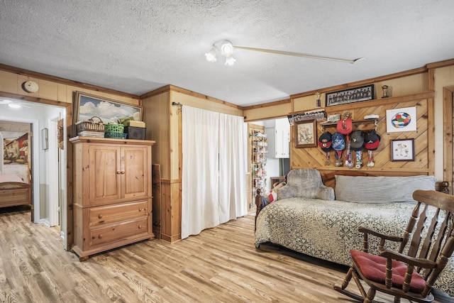 living area featuring wood walls, light wood-style flooring, and a textured ceiling