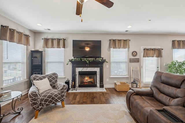 living room featuring visible vents, wood finished floors, a wealth of natural light, and a high end fireplace