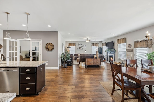 dining space featuring recessed lighting, dark wood-type flooring, a ceiling fan, a lit fireplace, and baseboards