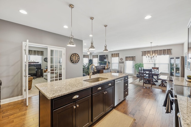 kitchen featuring appliances with stainless steel finishes, open floor plan, decorative light fixtures, french doors, and a sink