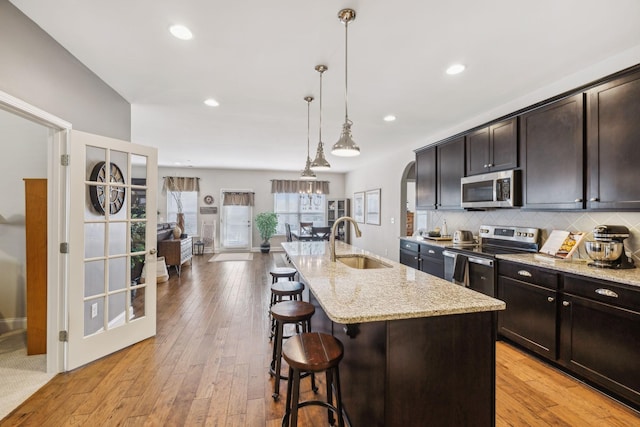 kitchen featuring hanging light fixtures, a center island with sink, appliances with stainless steel finishes, and a sink