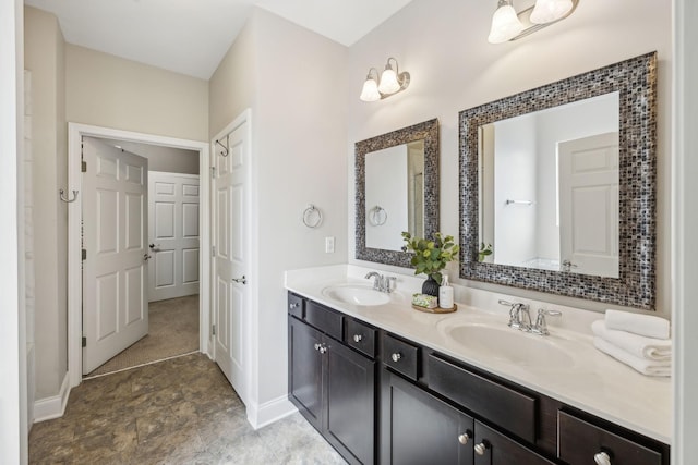 full bath with double vanity, a sink, and baseboards