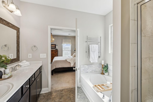 bathroom with double vanity, a garden tub, a sink, and ensuite bathroom