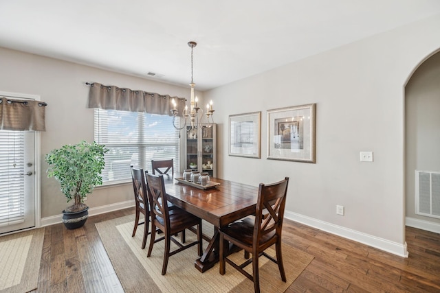 dining area featuring arched walkways, wood finished floors, visible vents, and an inviting chandelier