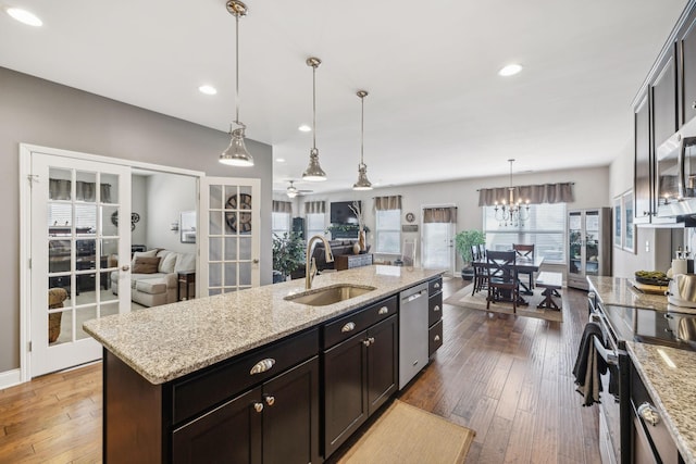 kitchen with stainless steel appliances, open floor plan, hanging light fixtures, and a sink