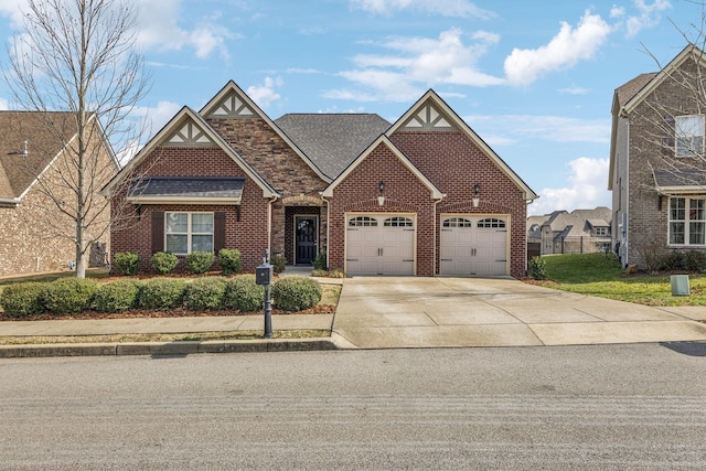 view of front facade featuring driveway, an attached garage, a shingled roof, and brick siding