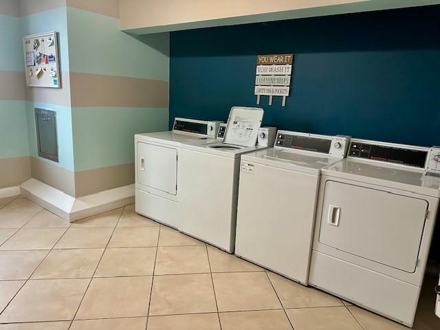 community laundry room featuring washer and dryer, baseboards, and light tile patterned floors