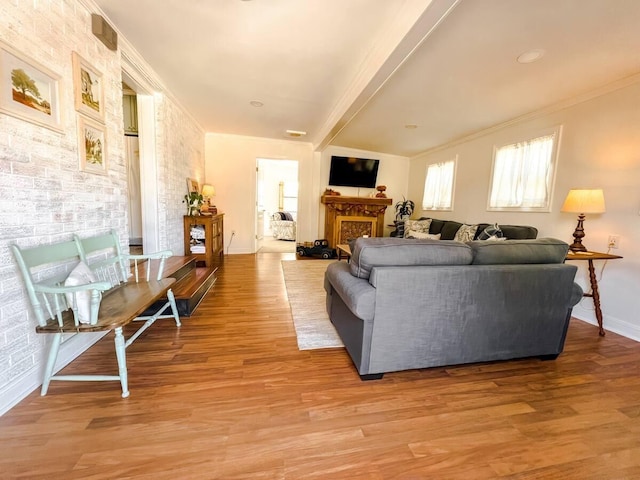 living area featuring ornamental molding, a fireplace, baseboards, and wood finished floors