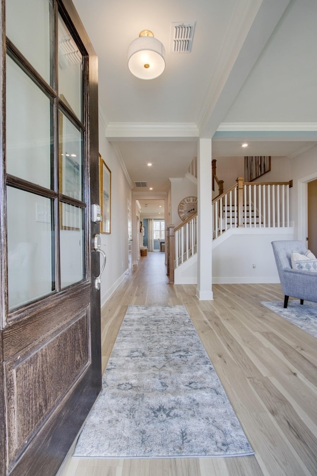 entryway with baseboards, visible vents, wood finished floors, stairs, and crown molding